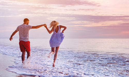 Couple holding hands walking on the beach