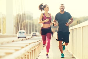 Fit couple jogging of side of bridge smiling