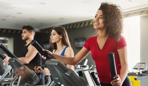 Young people exercising on cardio stepper in gym