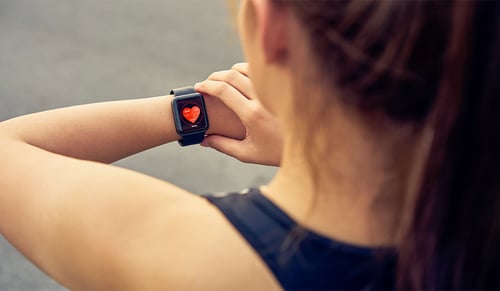 Young woman checking the sports watch measuring heart rate and performance after running