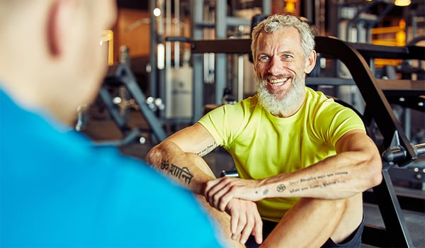 Portrait of a happy middle aged man discussing training results with fitness instructor or personal trainer