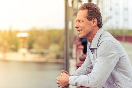 handsome mature sportsman listening music in earphones while running in park