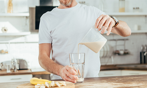 older-man-pouring-banana-protein-shake-at-home